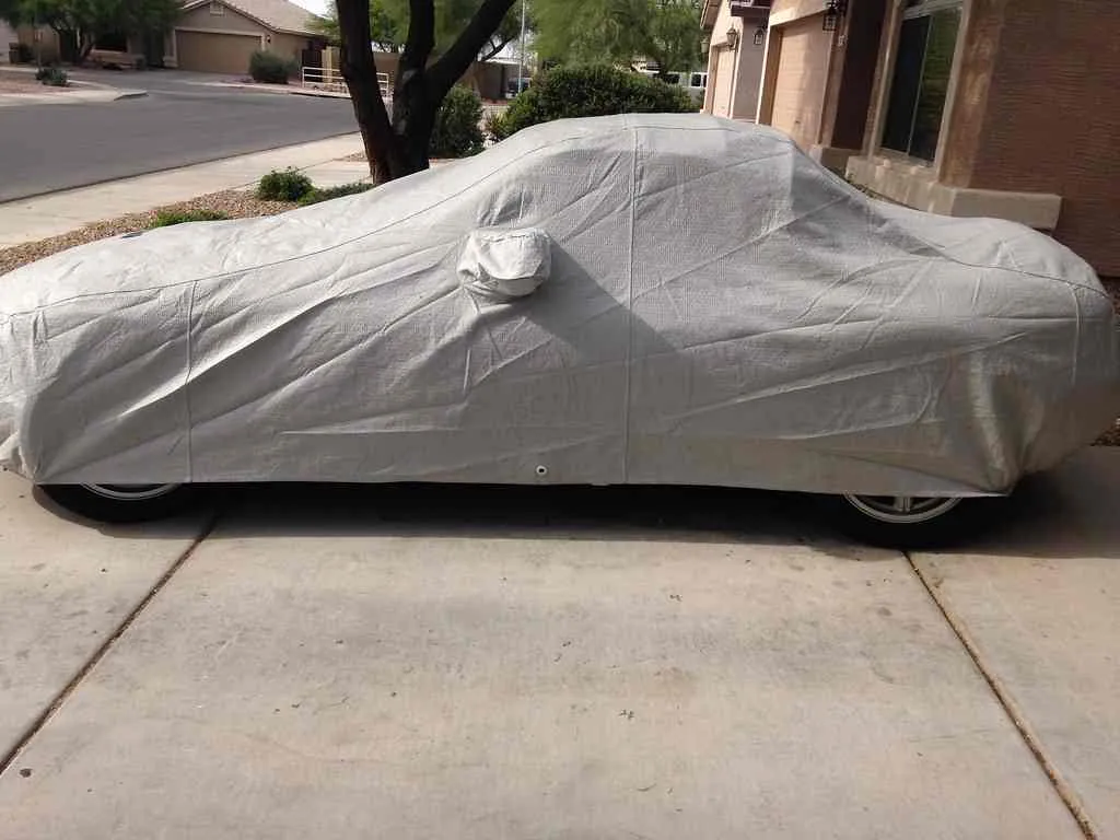 A car owner using a car cover to protect car paint from sun and scratches