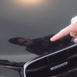 A boy pointing on car's bumper having paint chip scratches